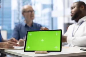 Advisor and elderly people exploring financial options in modern office, using green screen on tablet. Broker presenting life insurance plans of securing their savings for pension. photo