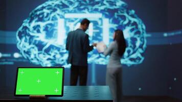 AI programmers colleagues using green screen laptop for business data analysis. IT experts in high tech location work on chroma key notebook to automatize tasks using artificial intelligence, camera B photo