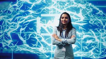 Portrait of smiling IT specialist standing with arms crossed in front of cutting edge display featuring AI and neural network graphics. Researcher in startup doing advancements in AI field, camera B photo