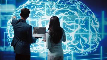Coworkers doing brainstorming, using devices to fix artificial intelligence neural networks. High tech workspace colleagues using AI system aiding in processing and transmitting information, camera B photo