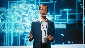 Presenter talking in front of world leading technology specialists and researchers meeting at artificial intelligence conference. Data scientist showcasing latest innovations in AI industry, camera A photo