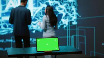 AI programmers colleagues using green screen laptop for business data analysis. IT experts in high tech location work on chroma key notebook to automatize tasks using artificial intelligence, camera A photo