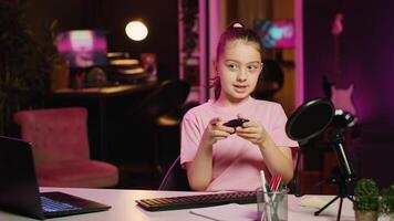 Kid content creator filming keyboard review in home studio, pressing different buttons to show typing capabilities. Little girl showcasing computer peripherals to audience on gen Z online channel photo