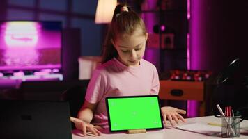 Cute child content creator filming technology review of newly released isolated screen tablet, unpacking it and presenting specifications to audience. Young online star showing mockup device to fans photo