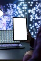 Economic analyst uses white screen layout on tablet in office, working at night inside urban skyscraper. Rich executive board member holding gadget with isolated blank mockup, legal analytics. photo
