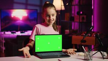 Child tech content creator filming technology review of green screen laptop, unboxing it and presenting specifications to audience. Kid influencer showing mockup notebook device to viewers photo