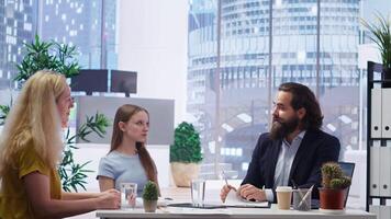 Financial advisor using laptop in office to present clients volatile stock exchange prices going up and down. Family getting consulted on forex trading platforms by brokerage firm expert, camera B video
