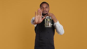 Waiter in uniform showing a stop sign with his palm raised in studio, expressing negative symbol and refusal about something. Showing rejection and being dissatisfied. Camera B. video