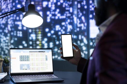 Board member checks white screen on mobile phone layout, analyzing transactions and revenue to expand company activity. CFO working with blank copyspace template and global data at night. photo