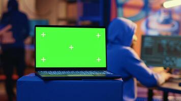 Green screen laptop used by hackers in underground hideout to write lines of code, developing virus that get past security systems. Chroma key device used by evil developers in hidden bunker photo