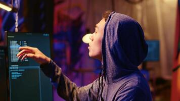 Hooded hacker talking with colleague while coding malware designed to exploit network backdoors, bypassing security measures such as logins and password protections, close up shot photo