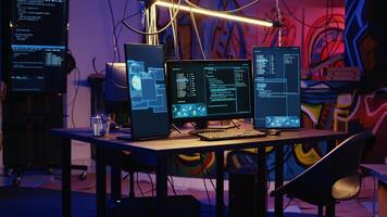 Jib down shot of advanced technology computer system running malicious code in empty warehouse. PC monitors in empty graffiti painted underground hideout used by hackers to commit illicit activities photo