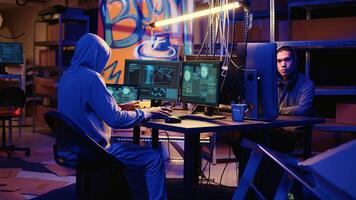 Rogue computer scientist arriving with laptop in underground warehouse, starting work on malware that get past security systems. Hacker in hidden HQ building scripts that can hack devices photo