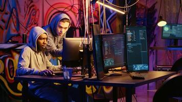 Beginner hacker requesting help from experienced cybercriminal, learning how to destroy firewalls and infect victim computer. Cracker in secret hideout teaches script kiddie how to write malware code photo