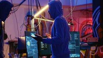 Rogue hacker group leader welcoming new member in hidden underground base, ready to teach him how to get past anti tamper measures implemented by companies to protect their products photo