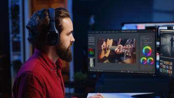 editor adds sound effects to filmed footage, working in post production creative studio. Videographer using headphones to test and improve audio quality, editing clips with professional software photo