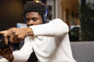 African american man focused on defeating enemies while playing videogames on gaming console with teammates. Player fights foes in esports game using gamepad, chatting with friends through headset photo