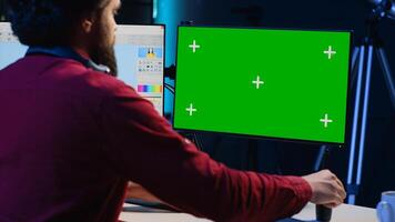 Photographer using advanced photo editing software on green screen monitor to make improvement to images quality. Photo editor utilizing specialized photographs retouching application on mockup PC