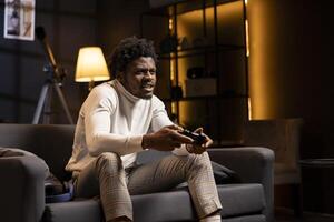 Man looking in disbelief at smart TV display while playing videogames, receiving game over screen on gaming console. Gamer upset after being defeated by rival players in online esports competition photo
