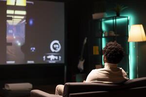 Gamer in front of ultrawide smart TV, watching first person shooter videogame gameplay. African american man in home theatre using high tech television set to see gaming content online photo