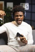 Gamer feeling relieved after winning videogame level, screaming at television set in excitement. Pleased man at home yelling from joy after seeing achieving victory while playing on gaming console photo
