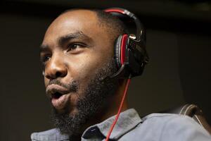 Professional streamer competing in intense online multiplayer videogame, streaming live at home, close up shot. Man playing on gaming PC, using headphones to talk with audience photo