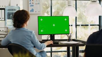 Business manager working at monitor showing blank greenscreen template, sitting at office workstation during program. Analyst using desktop monitor with isolated chromakey copyspace layout. photo