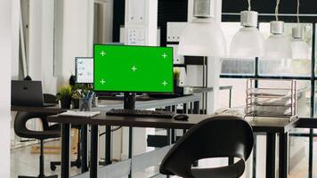 Greenscreen monitor in coworking space running on desk, open floor plan small business office. Computer showing isolated mockup template with blank chromakey screen, modern career. photo