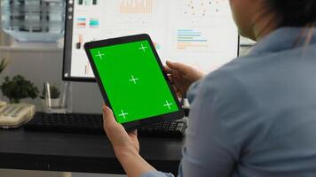 Office worker examines greenscreen layout in coworking space, working on business operations and looking at isolated chromakey display. Woman holding tablet with blank copyspace. photo