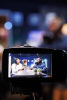 Selective focus on professional camera screen recording bloggers streaming live internet radio using microphones from home studio. Black couple filming vlog for social media platform photo