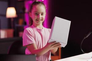 Portrait of kid content creator using high quality recording gear to shoot product unboxing for streaming channel on online platforms. Child warmly welcoming fans, filming electronics unpacking photo