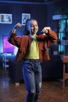 Cute girl performing trending dance routine in living room, surrounded by computer screens displaying 3D animations. Small child dancing inside neon lit home studio, creating content for online fans photo
