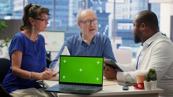 Broker helping old couple with retirement plans options at a financial counseling meeting, working with chroma key display. Elderly couple asking insurance expert about financial options. Camera A. photo