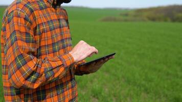 Young farmer working in a wheat field, inspecting and tuning irrigation center pivot sprinkler system on tablet video