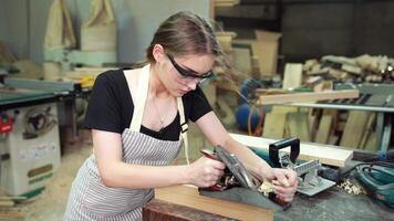 Attractive middle aged woman carpenter designer works with ruler, make notches on the tree in workshop. Image of modern femininity. Concept of professionally motivated women video