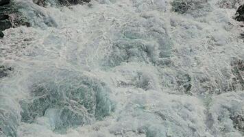 Turbulent Waters in Motion, A close-up view of turbulent waters in motion, capturing the frothy and swirling patterns of the water as it rushes over rocks. video