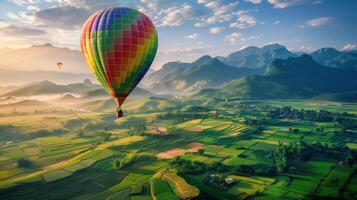 A colorful hot air balloon floating gracefully over a patchwork of green fields and distant mountains photo
