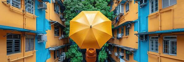 A person holding a yellow umbrella near a building photo