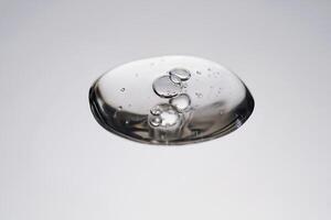 A drop of cosmetic product with bubbles on a gray background. photo