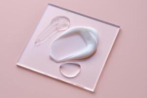 Textures of different cosmetic products on a pink background on a square transparent stand. photo