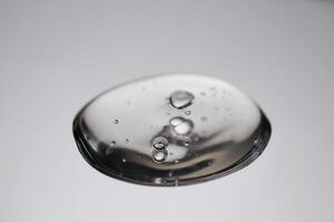 A drop of cosmetic product with bubbles on a gray background. photo