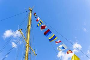 A close-up of a ship's mast with colorful signal flags flying photo