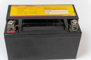 A black motorcycle battery with charging information and terminal posts photo