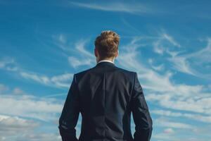 Businessman symbolizing ambition and success against clear blue sky, representing determination and achievement photo