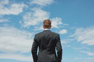 Rear view of a businessman in a suit looking at the sky, symbolizing ambition and future aspirations. photo