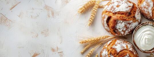Freshly baked pastries dusted with powdered sugar, accompanied by wheat and cream on a rustic background. photo