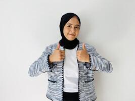 Young Muslim woman smiling and making thumbs up on. Approval gesture isolated by white background. photo