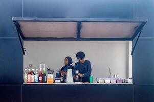 An open coffee shop bar shows two male and female baristas mixing drinks for cafe visitors, Indonesia, 20 June 2024. photo