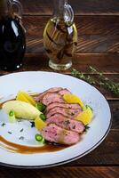 Roast duck fillet with mashed potato and orange sauce on wooden background photo