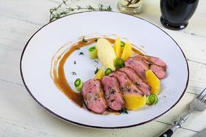 Roast duck fillet with mashed potato and orange sauce on wooden background photo